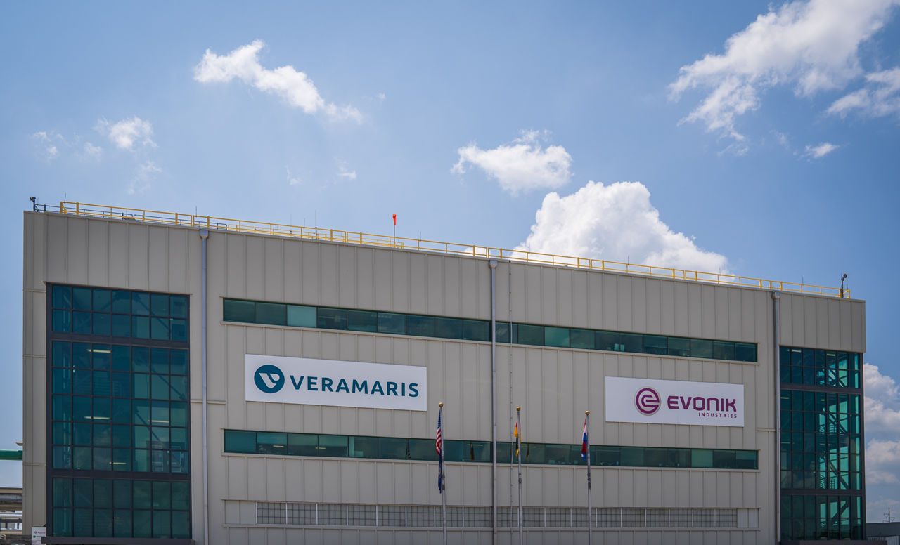 A large building with glass corners. The facade displays the logos of Veramaris and Evonik.