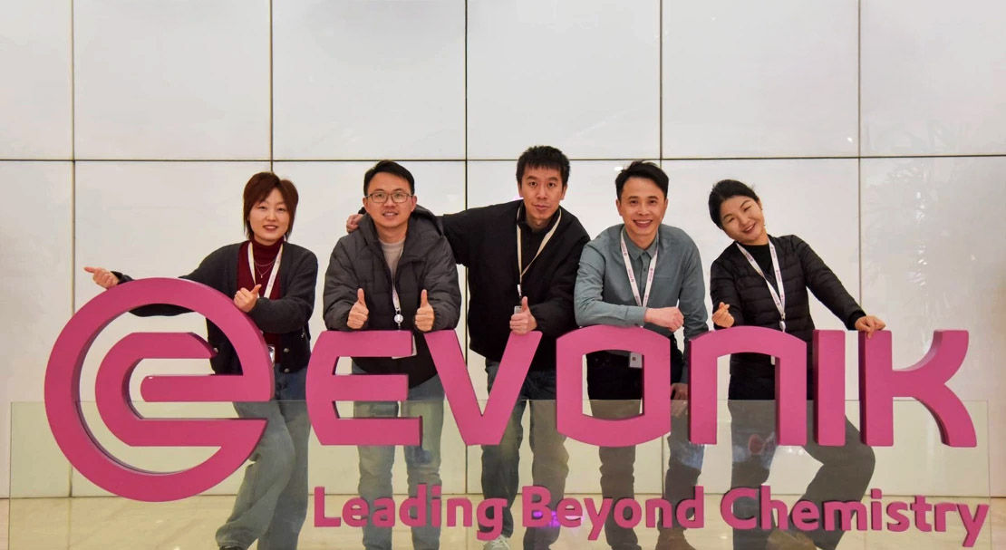 A group photo behind an Evonik logo