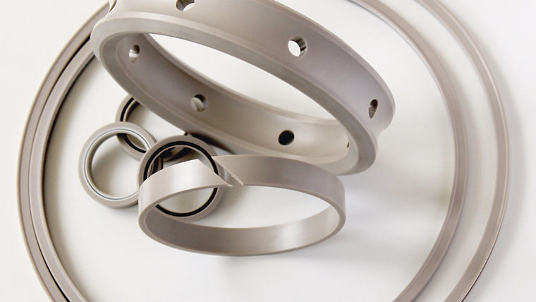 Various sizes of gray industrial sealing rings with smooth surfaces and holes are arranged on a white background.