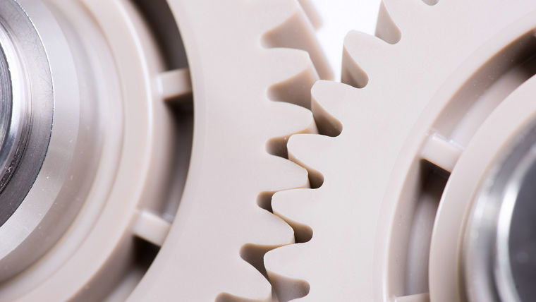 Close-up of intermeshing polymer gears on metal shafts, used in precision industrial or automotive applications