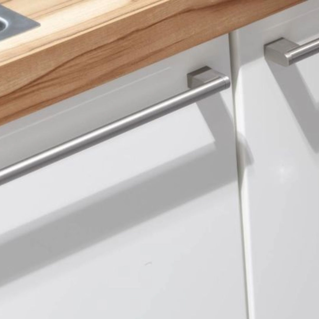 Close-up of white kitchen cabinets with metal handles and a wooden countertop.