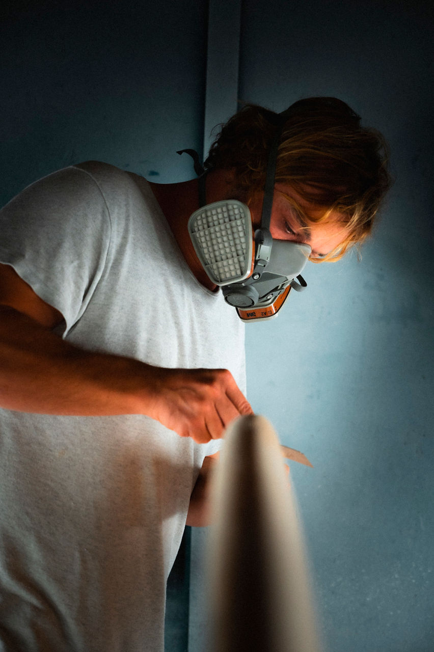 Thilo von Osterhausen smoothes the edge of a surfboard, known as the “rail,” with a scraper.