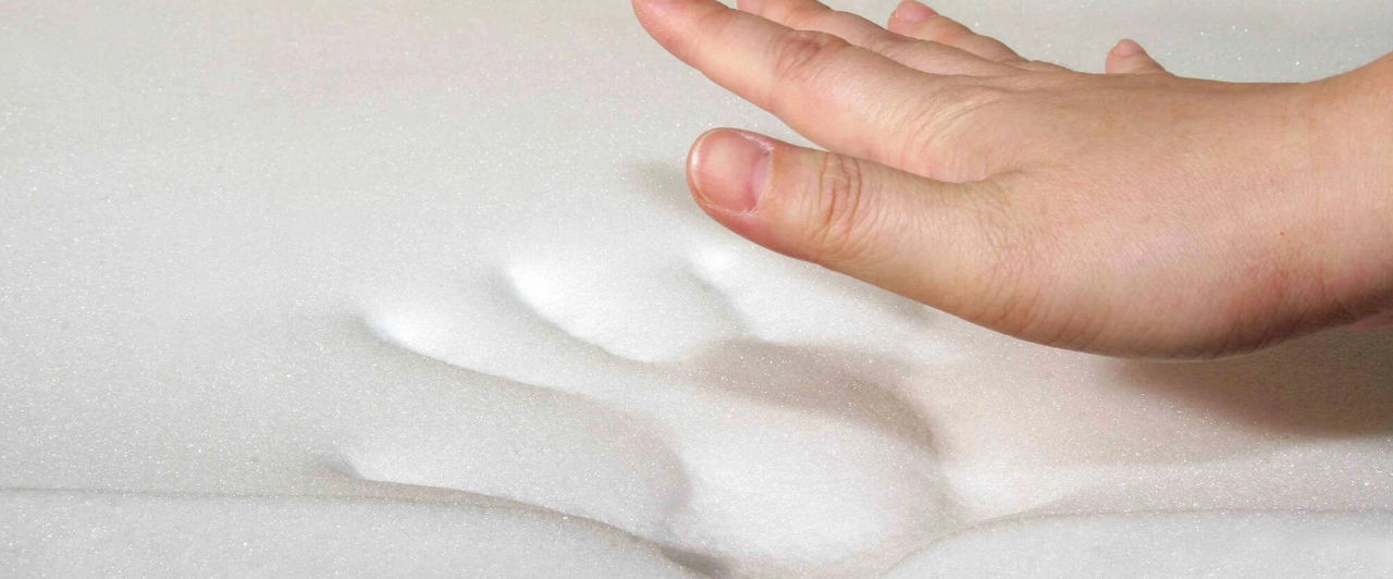 Hand pressing into viscoelastic PU foam showing memory and comfort properties