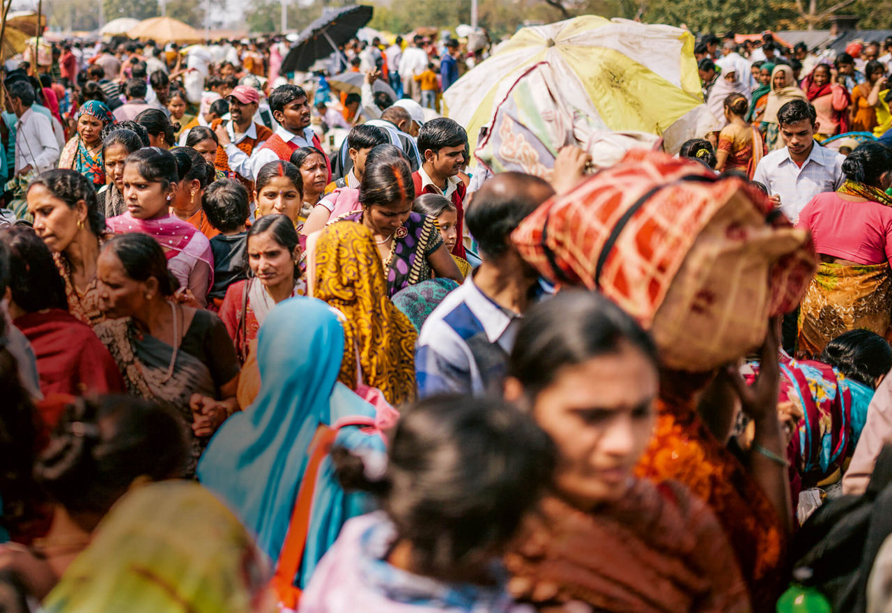 Street scene in India, many people in colorful clothes are on foot.