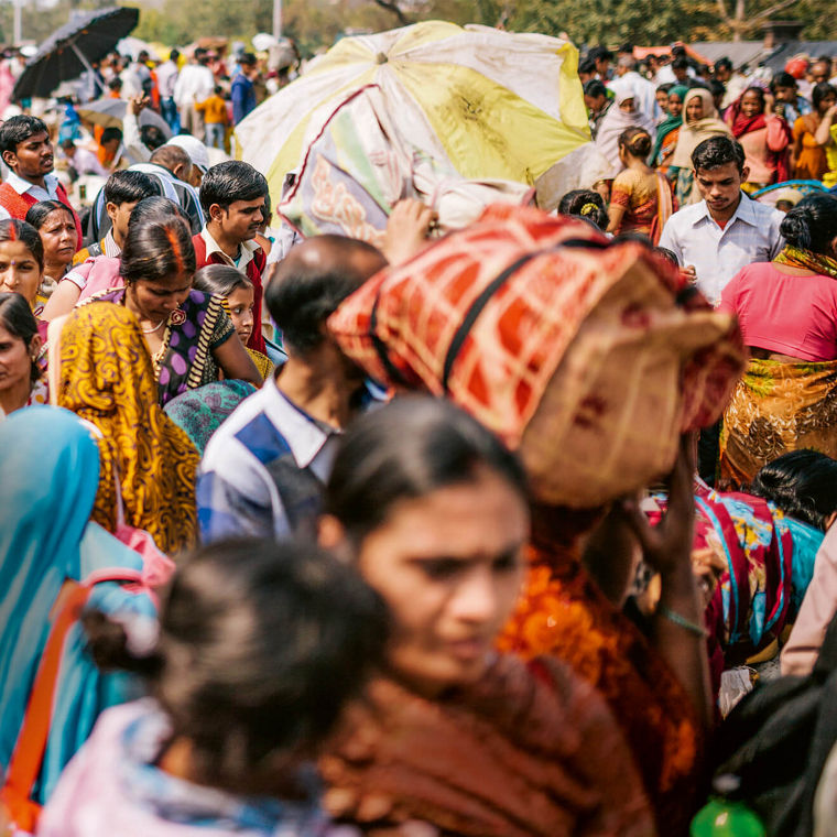 Straßenszene in Indien, viele Menschen in farbenfroher Kleidung sind zu Fuß unterwegs.