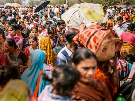 Straßenszene in Indien, viele Menschen in farbenfroher Kleidung sind zu Fuß unterwegs.