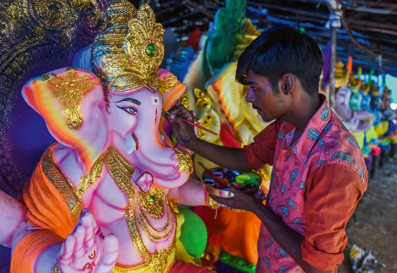 A man paints the figure of the Hindu deity.