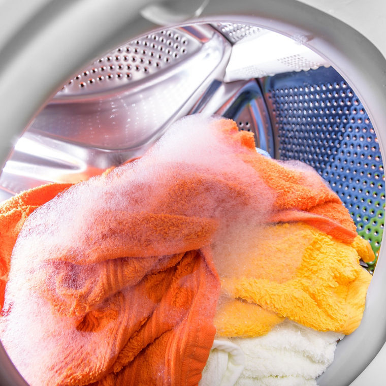 Die Trommel einer Waschmaschine mit farbiger Wäsche.