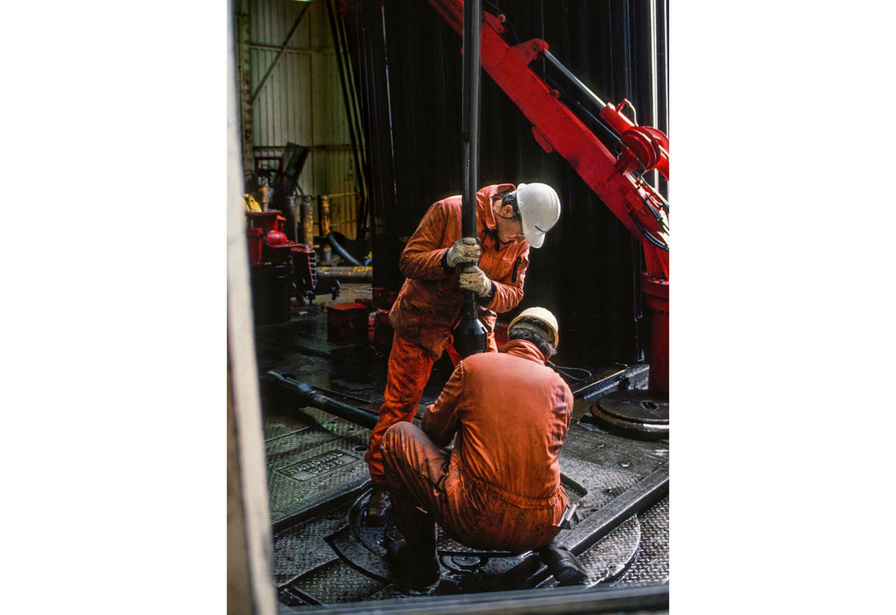 Zwei Arbeiter einer Bohrplattform passen eine Bohrstange ein.