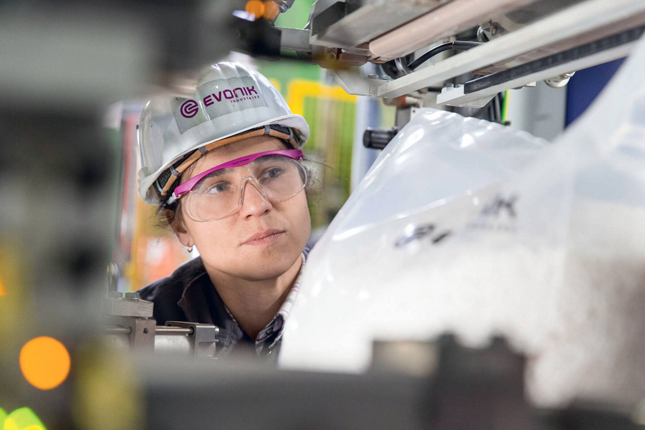 Eine Evonik-Mitarbeiterin blickt in die laufende Anlage.