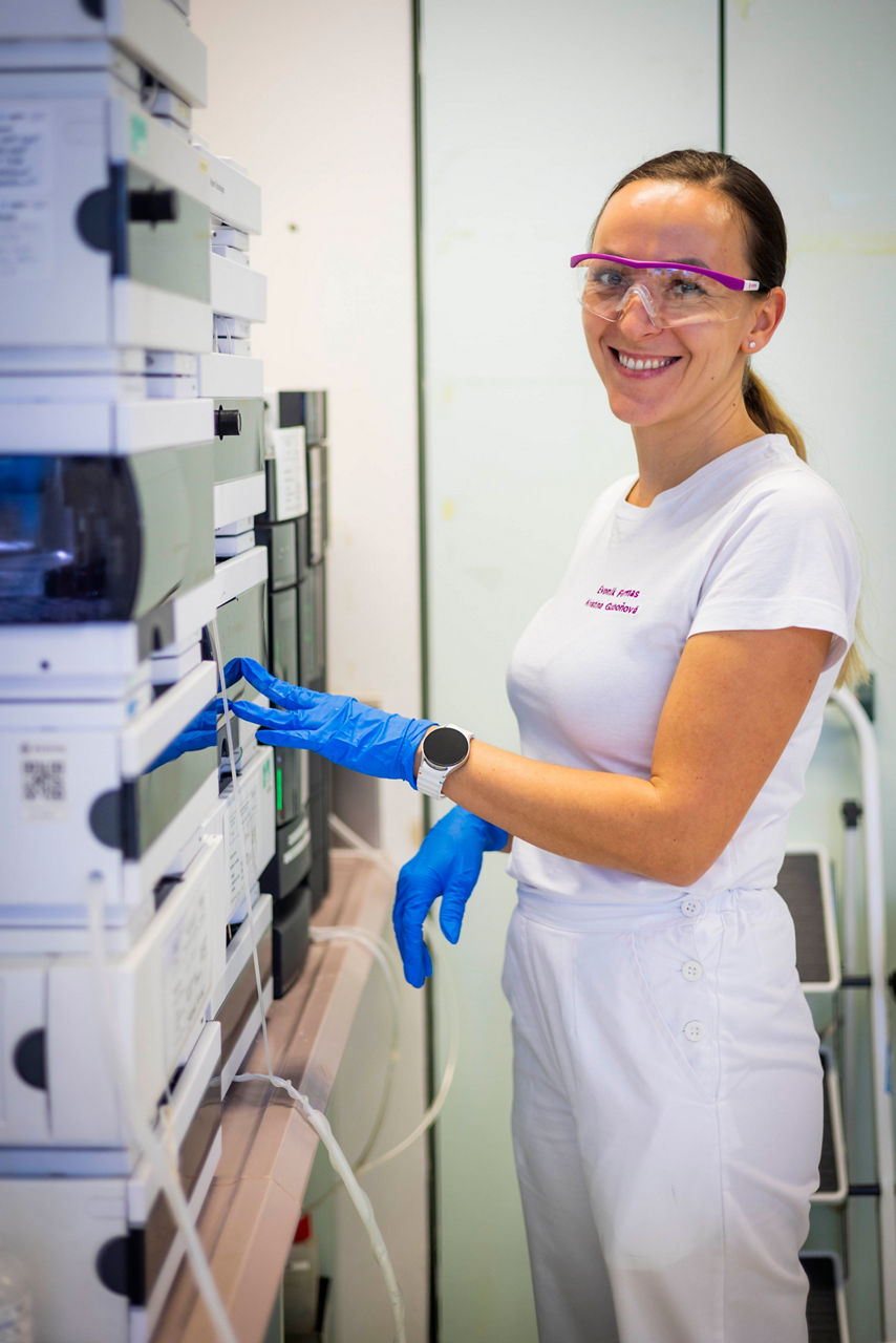 Lab technician Kristína Gaboňová stands at an instrument, dressed in a white lab coat.