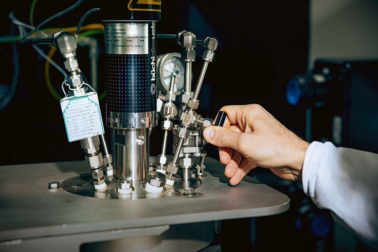 Eine Männerhand dreht an eienem kleinen Ventil an einer Edelstahlleitung.