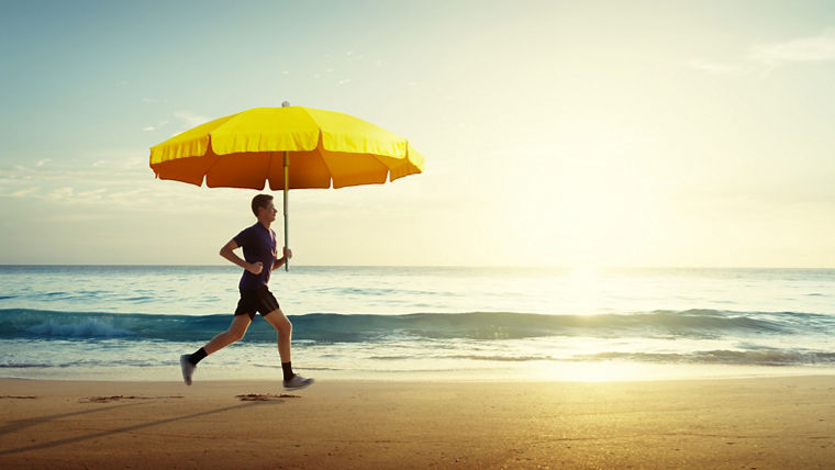 Man running on tropical beach at sunset