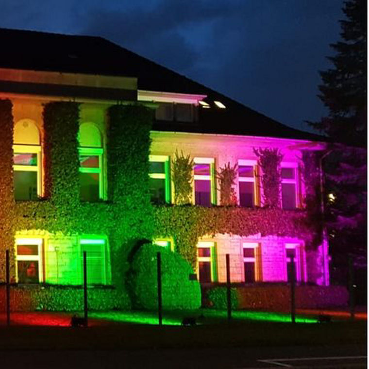 The building is illuminated in vibrant colors, creating a striking visual effect against the night sky.