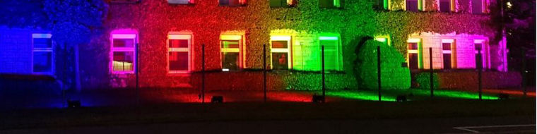 The building is illuminated in vibrant colors, creating a striking visual effect against the night sky.