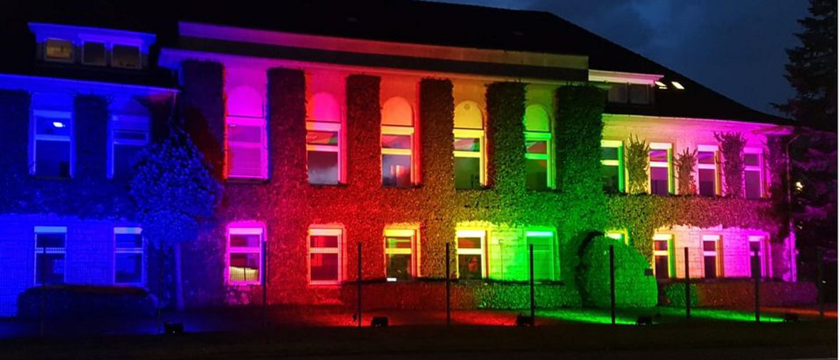 The building is illuminated in vibrant colors, creating a striking visual effect against the night sky.