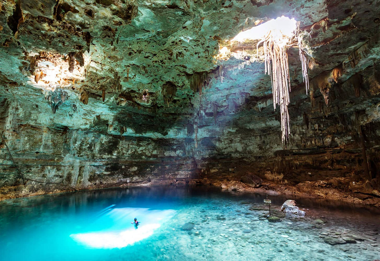 ein Schwimmer in einer türkisblauen Cenote