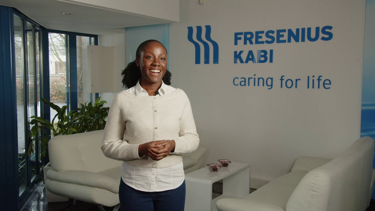 Binta lächelt vor dem Fresenius Logo und Slogan 