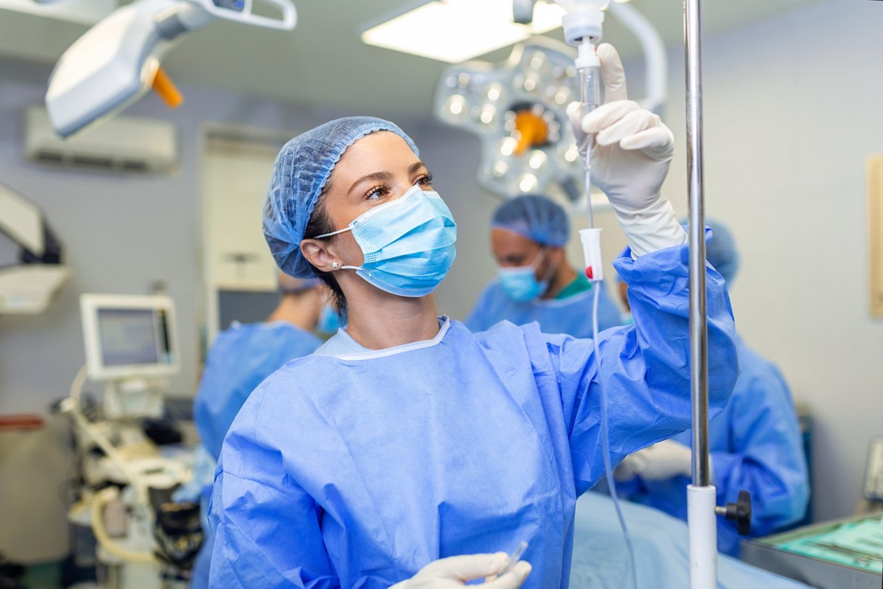 Female Doctor in the operating room putting drugs through an IV - surgery concepts