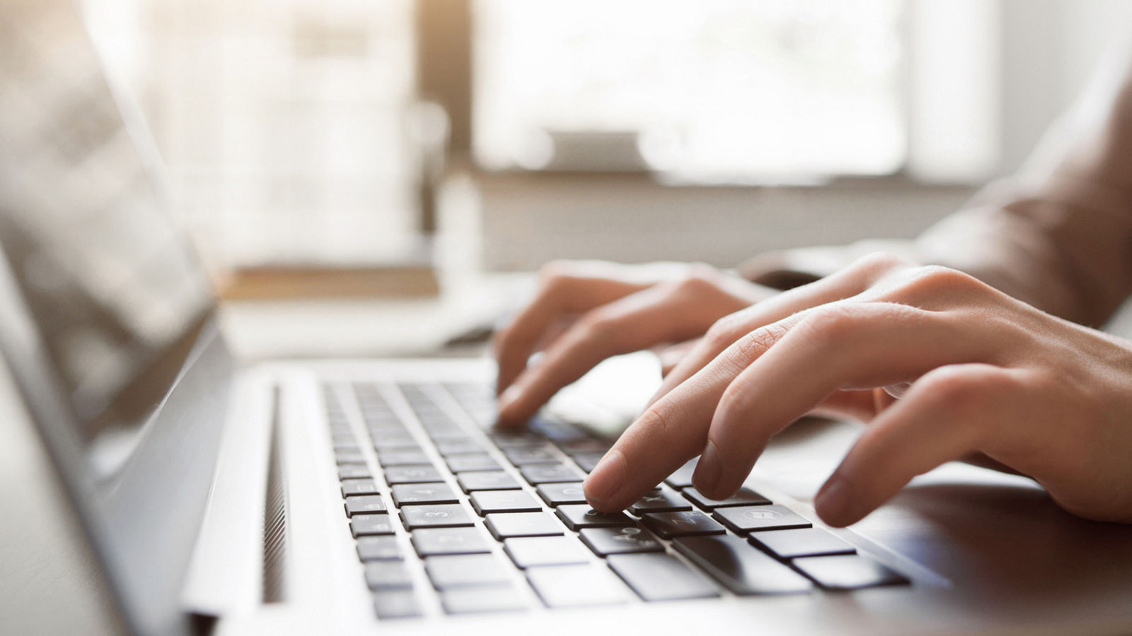 Typing on laptop closeup, chatting in Facebook