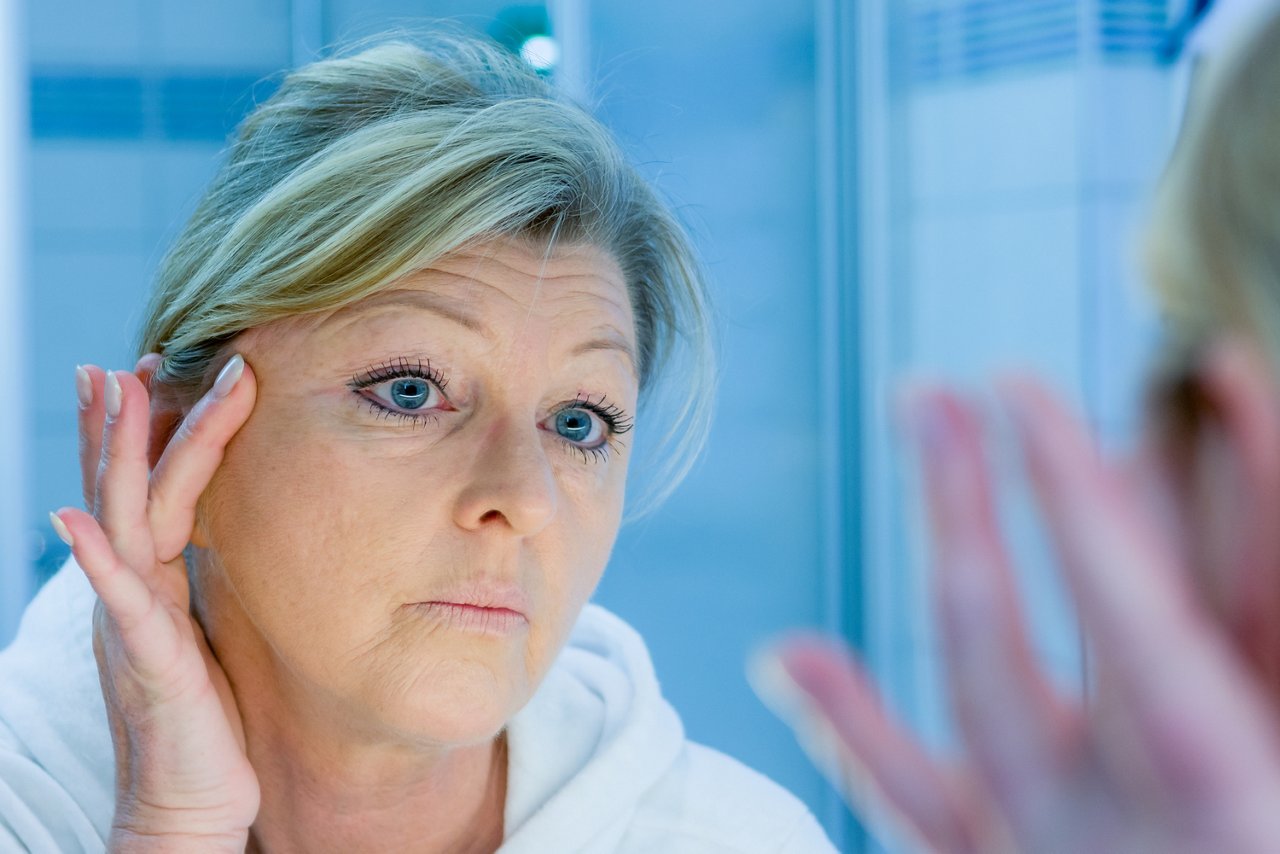 frau betrachtet ihre augenfältchen