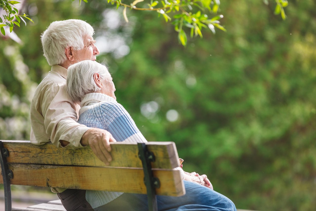 Älteres Paar auf der Parkbank genießen das Wetter
