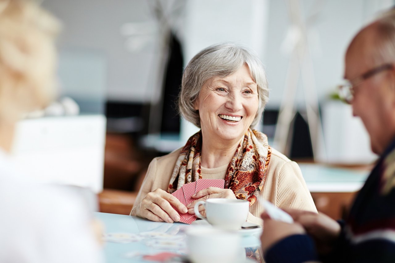 Freundliche Seniorin beim Kartenspielen