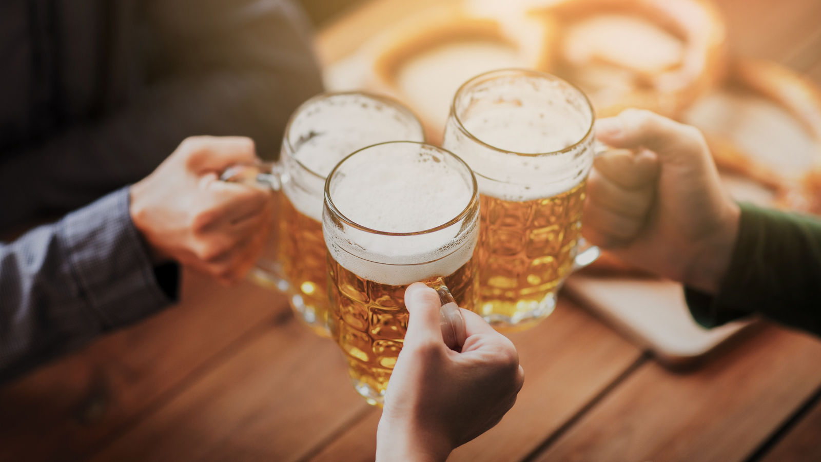 close up of hands with beer mugs at bar or pub