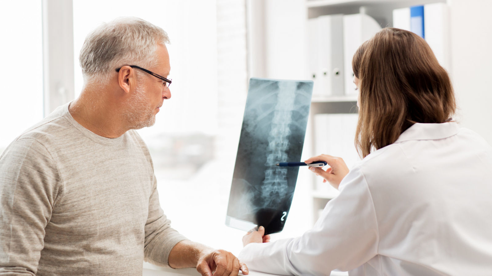 Ärztin bei Wirbelsäulen-Röntgenbild Besprechung mit Patienten