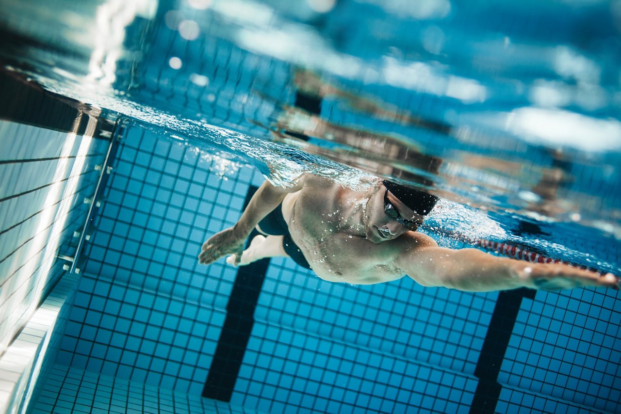 Underwater shot of professional male athlete swimming in pool. Young man swimming the front crawl in a pool.