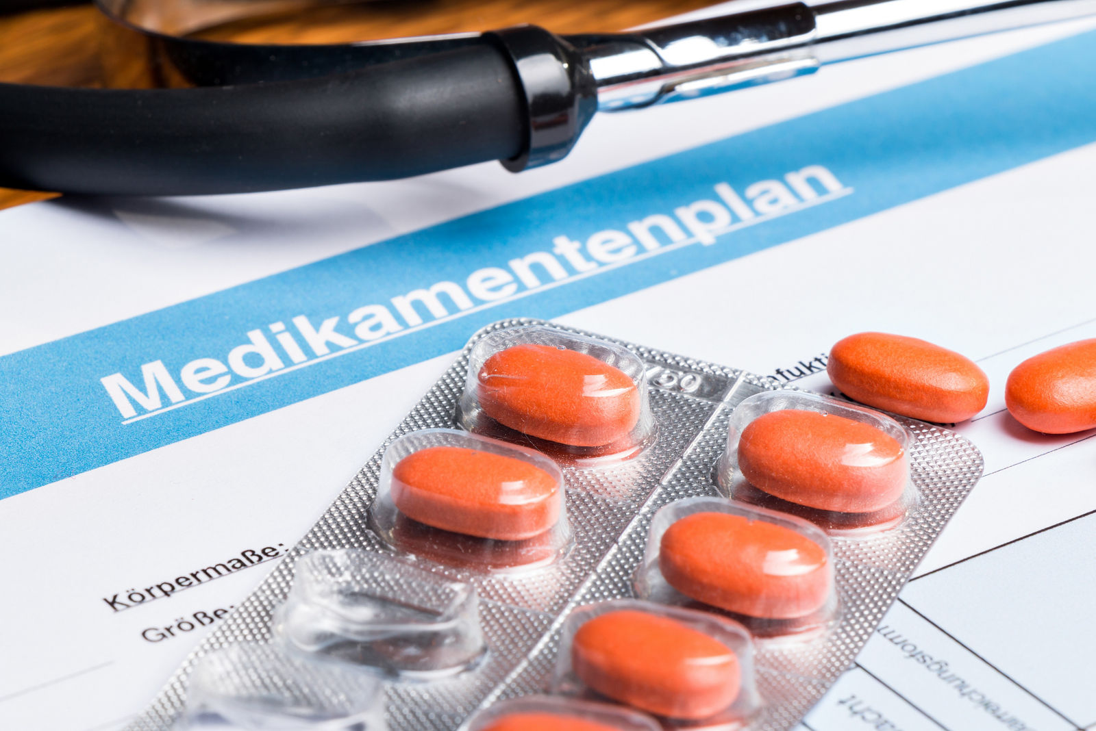 Tabletten mit Blister und Stethoskop liegen auf einen Medikamentenplan