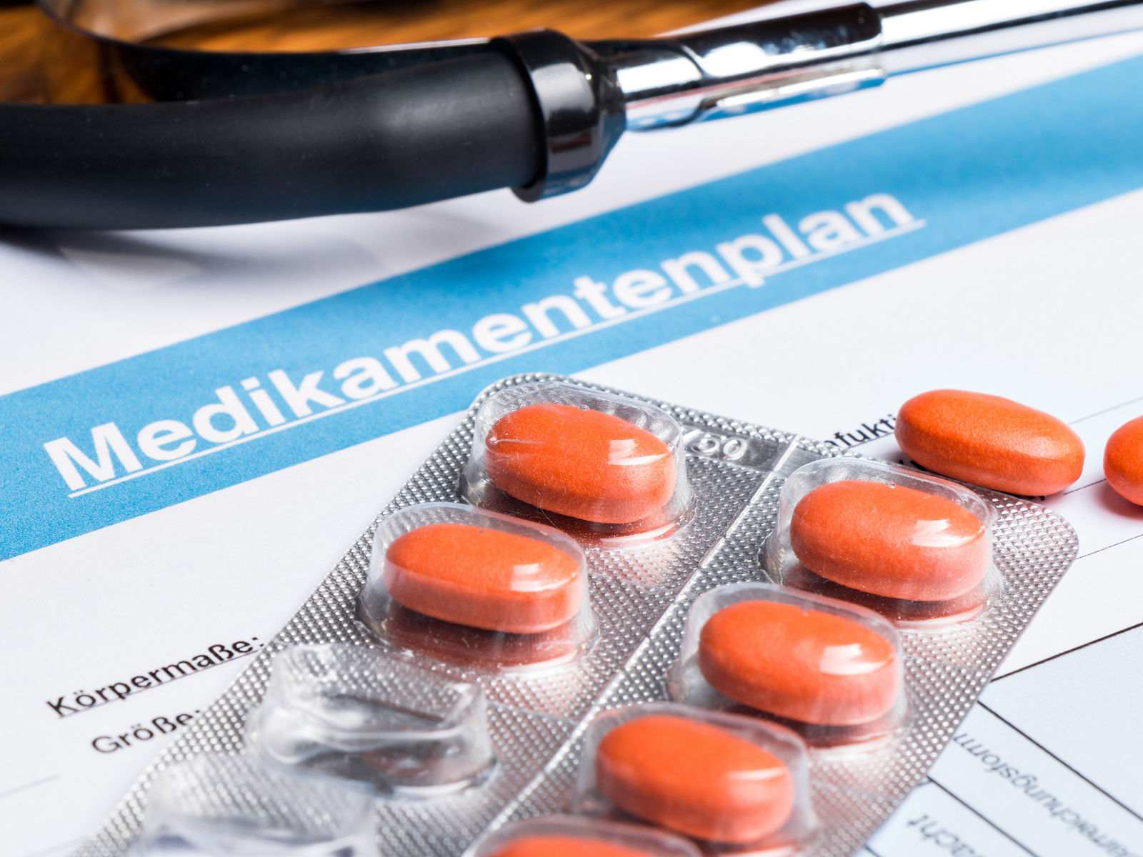 Tabletten mit Blister und Stethoskop liegen auf einen Medikamentenplan