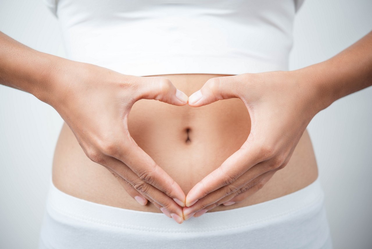Close up of woman's hands made heart on belly isolated on white background.health care concept