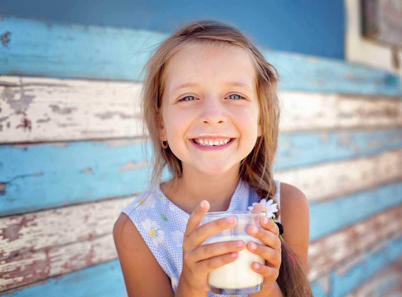 Cute little girl is drinking milk outdoors