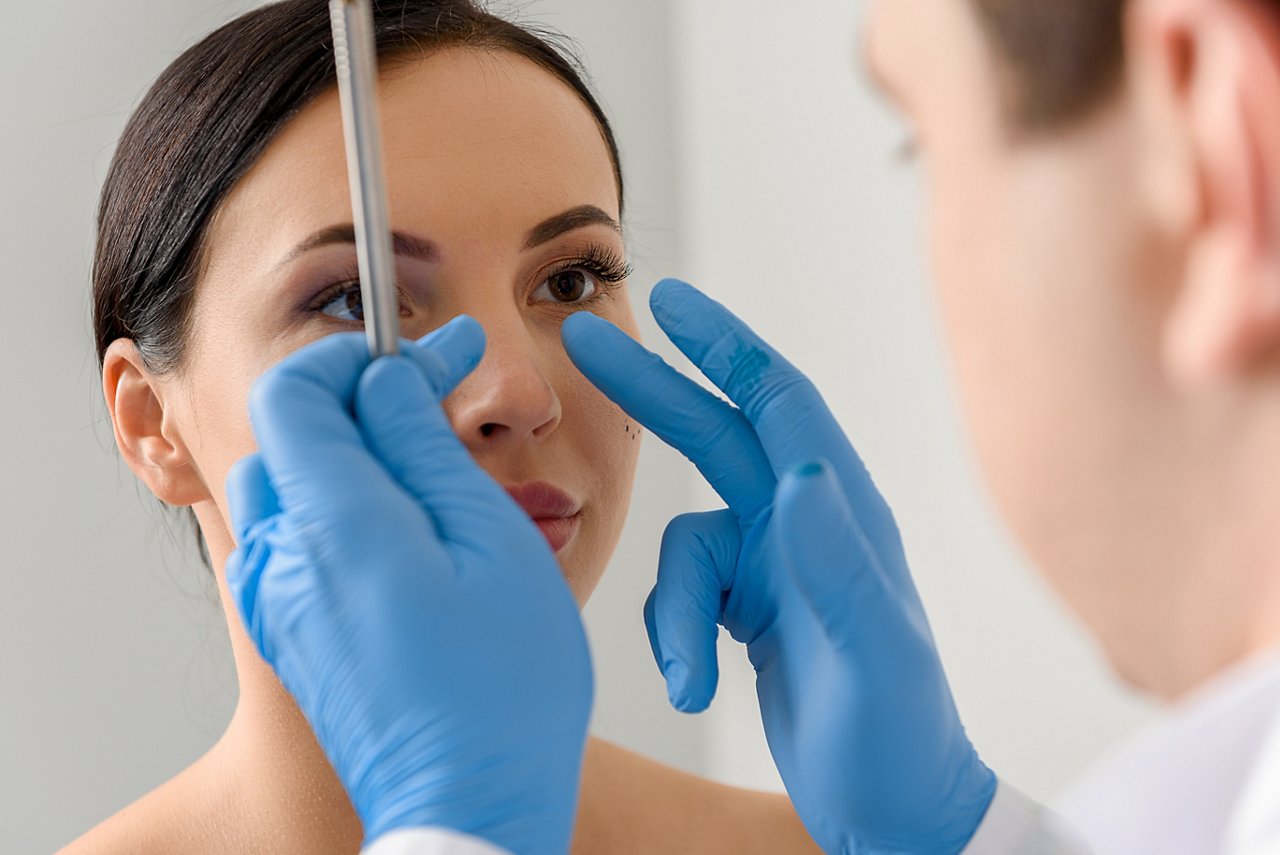 Focus on doctor hands showing where correct nose of calm woman. She watching at therapeutic