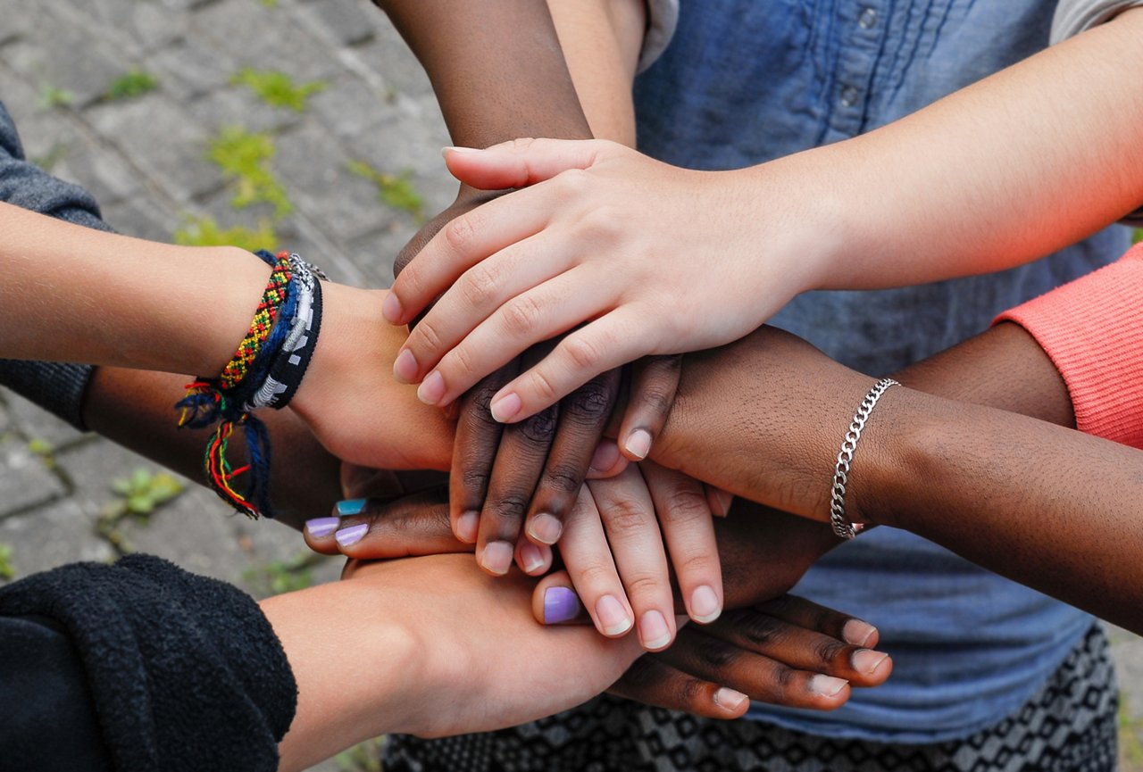 Multiracial teenagers joining hands together in cooperation