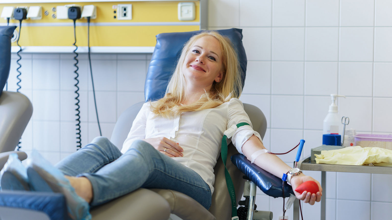 young caucasian woman with toy heart in the hand donates blood for saving lives and medical research