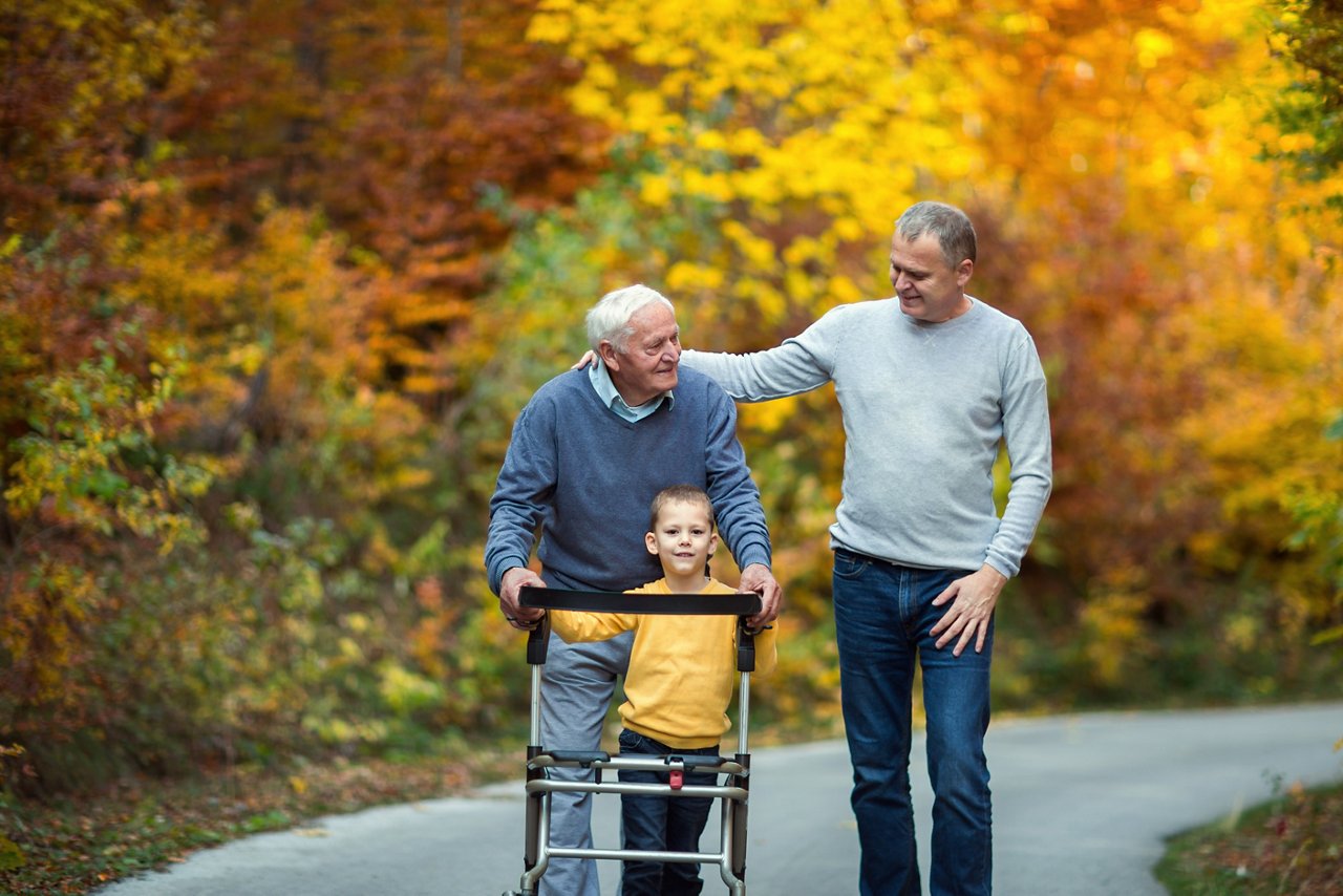 Elderly father adult son and grandson out for a walk in the park. 