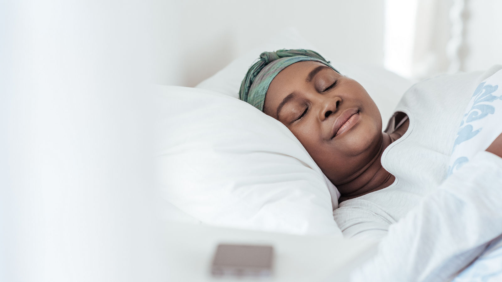 Young African woman wearing a headscarf sleeping in bed