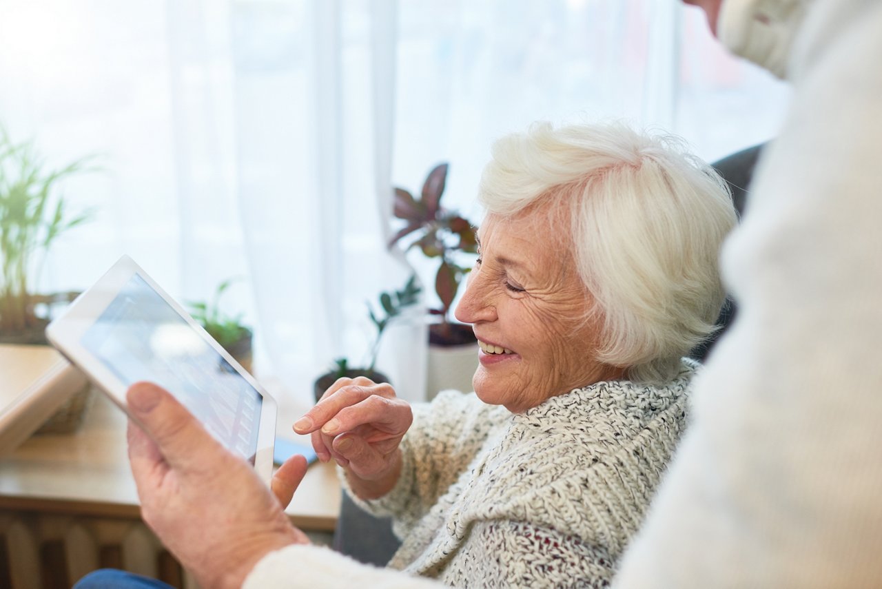 Side view portrait of senior woman using digital tablet and laughing happily