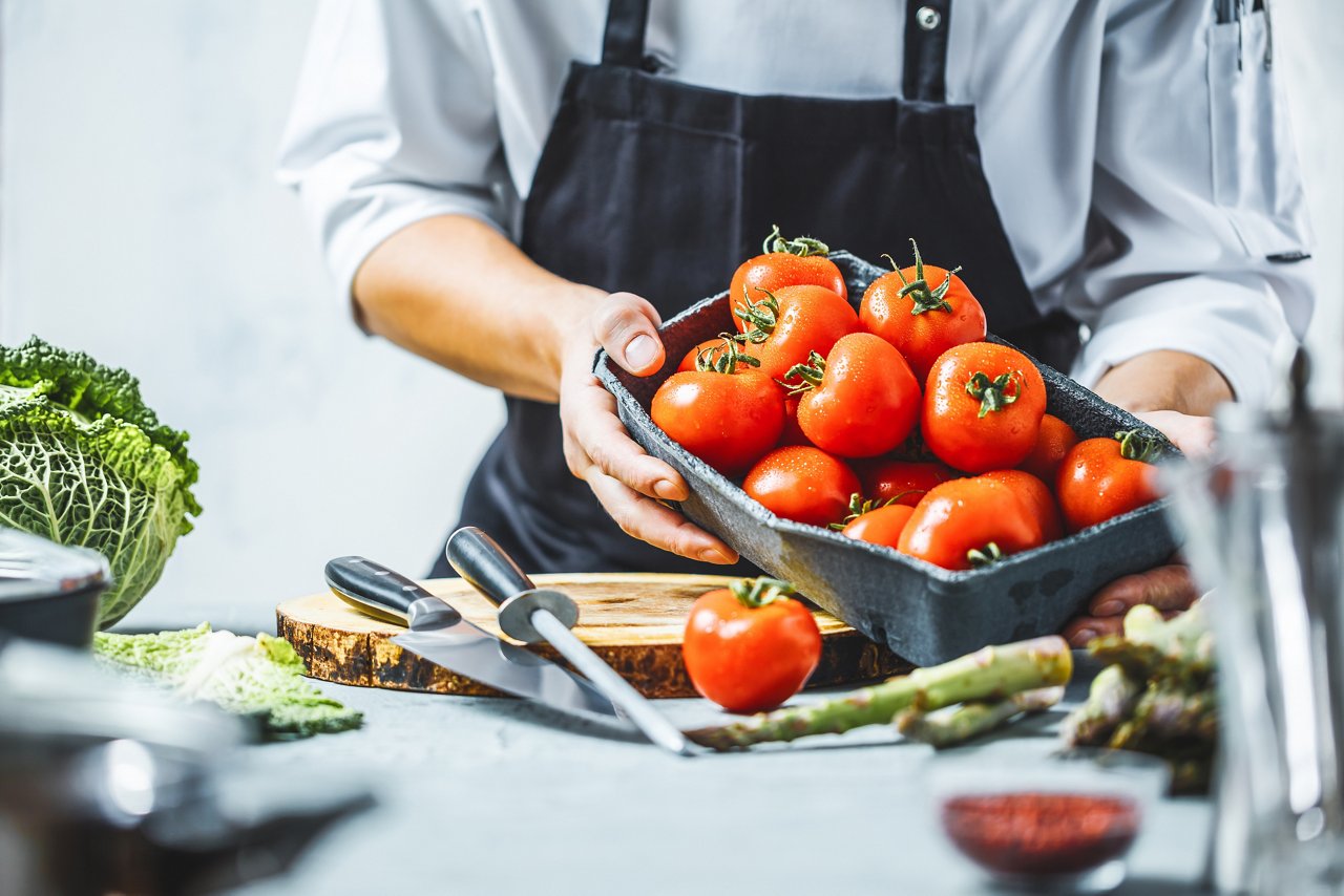 Chefkoch in der Küche mit frischem Gemüse (Tomaten)