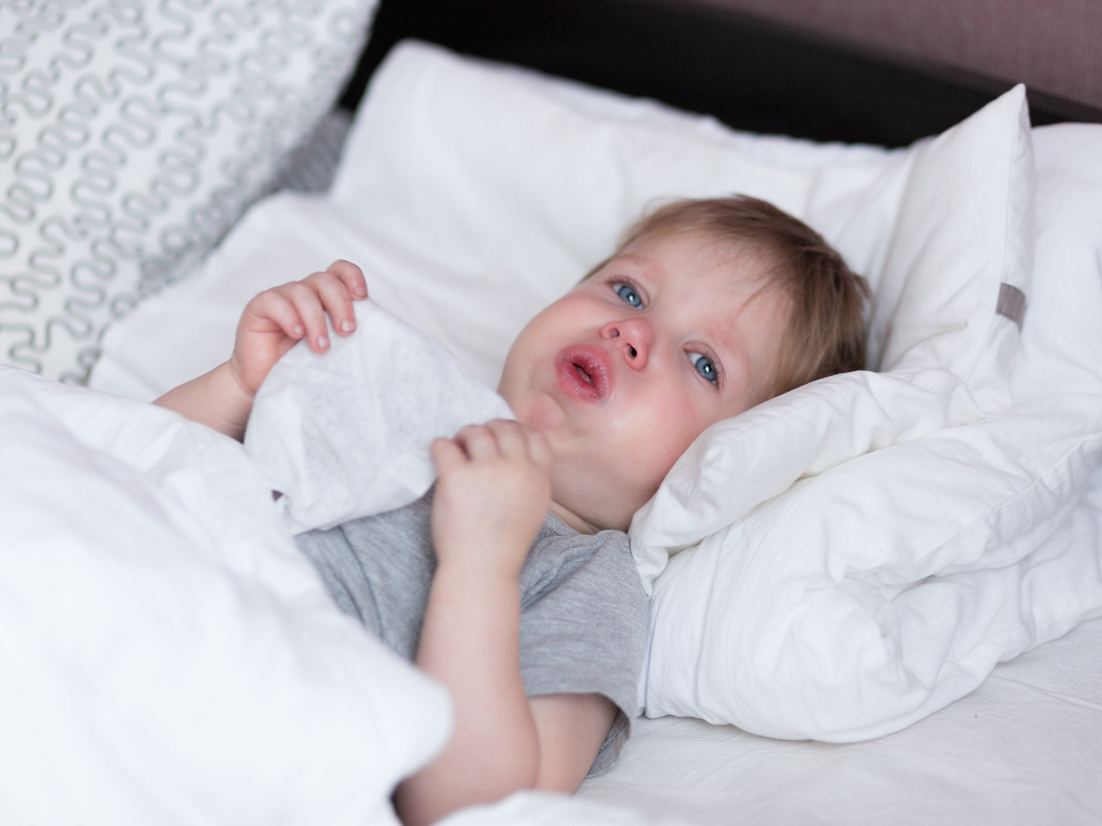 Little kid boy with sore throat cough in the bed close-up