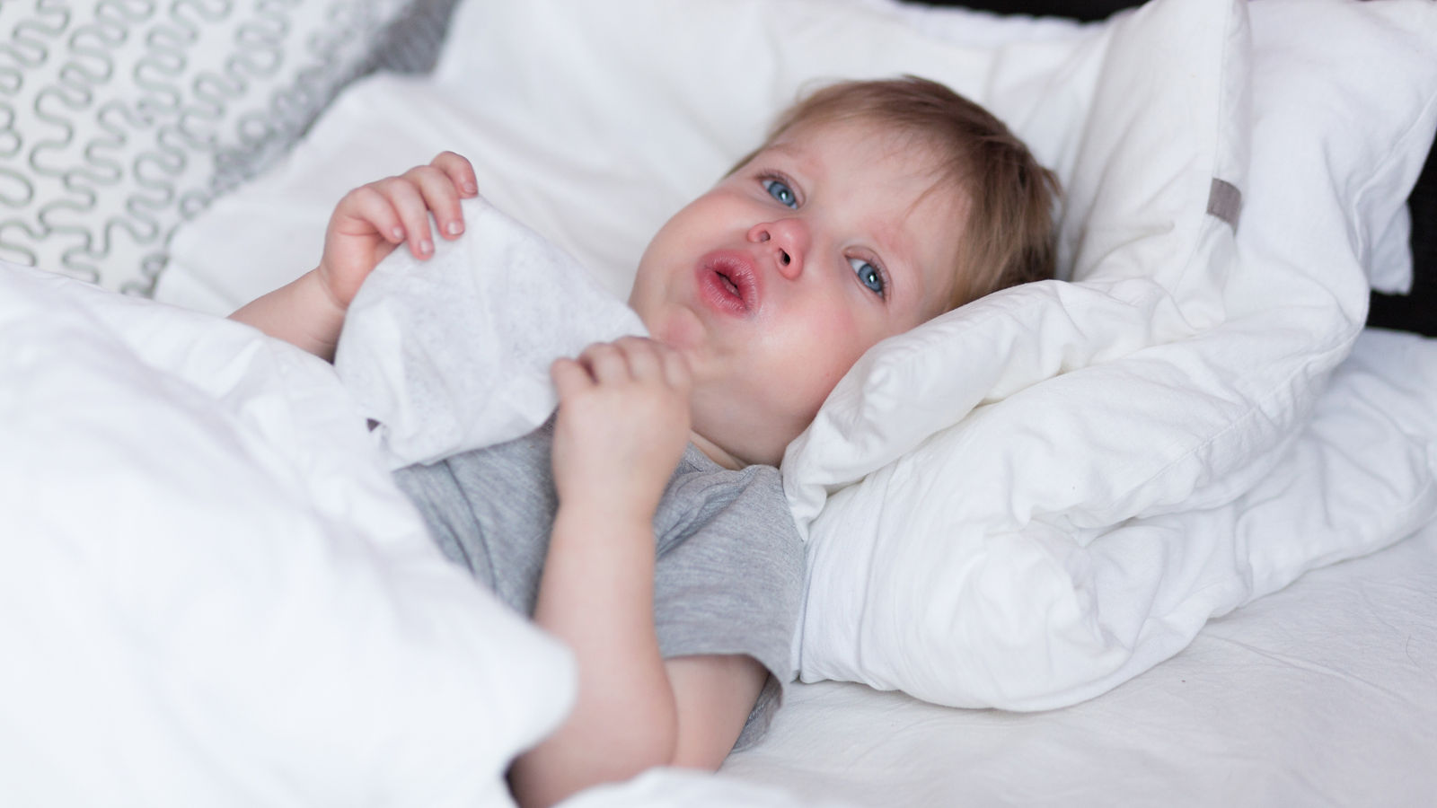 Little kid boy with sore throat cough in the bed close-up