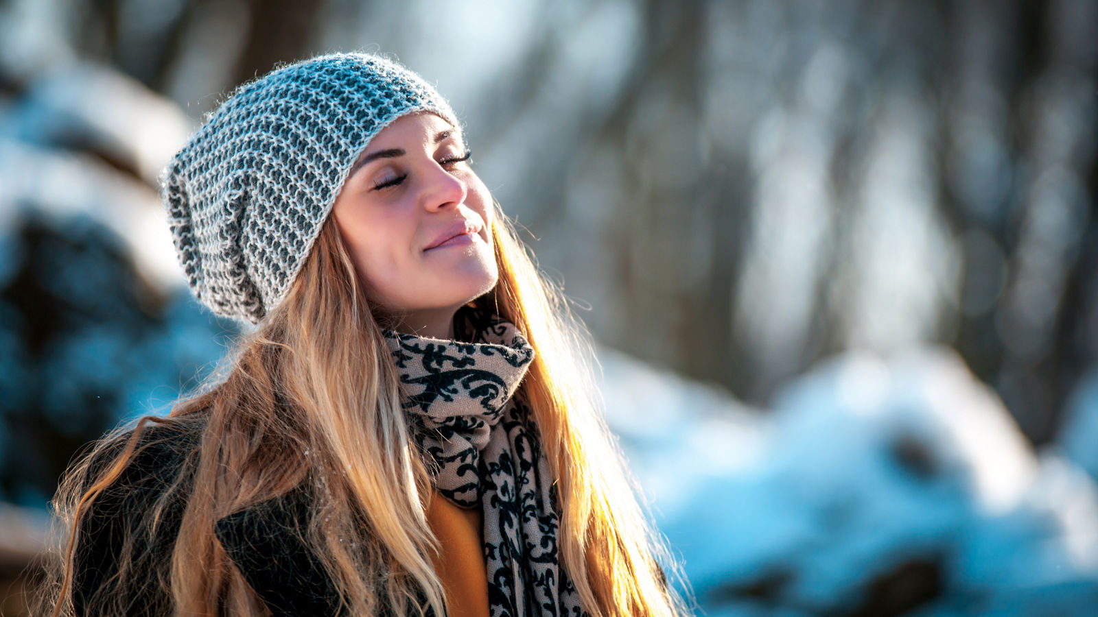Young woman in the winter park at sunny day, warm clothes