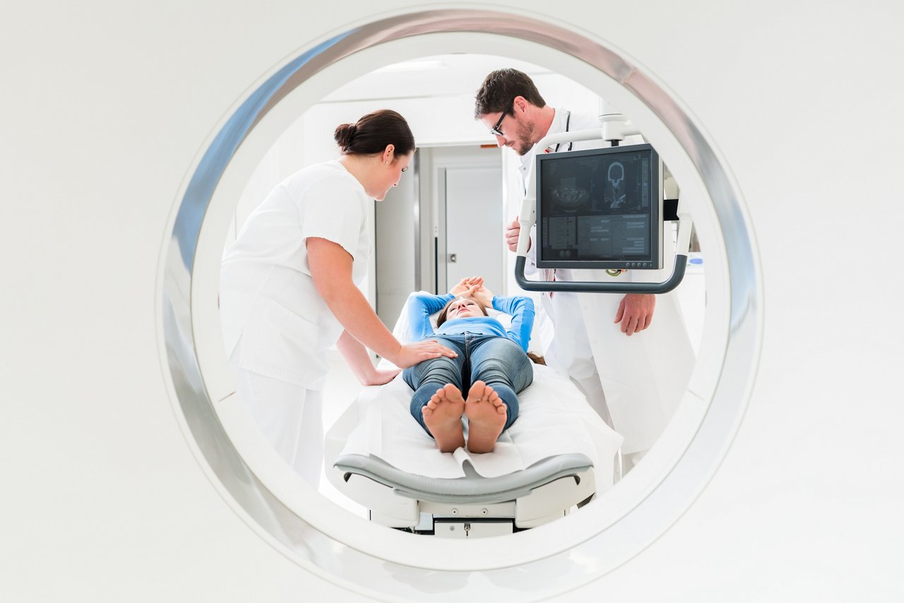 Doctor, nurse, and patient at CT scan tomography in hospital, shot through the tube of device