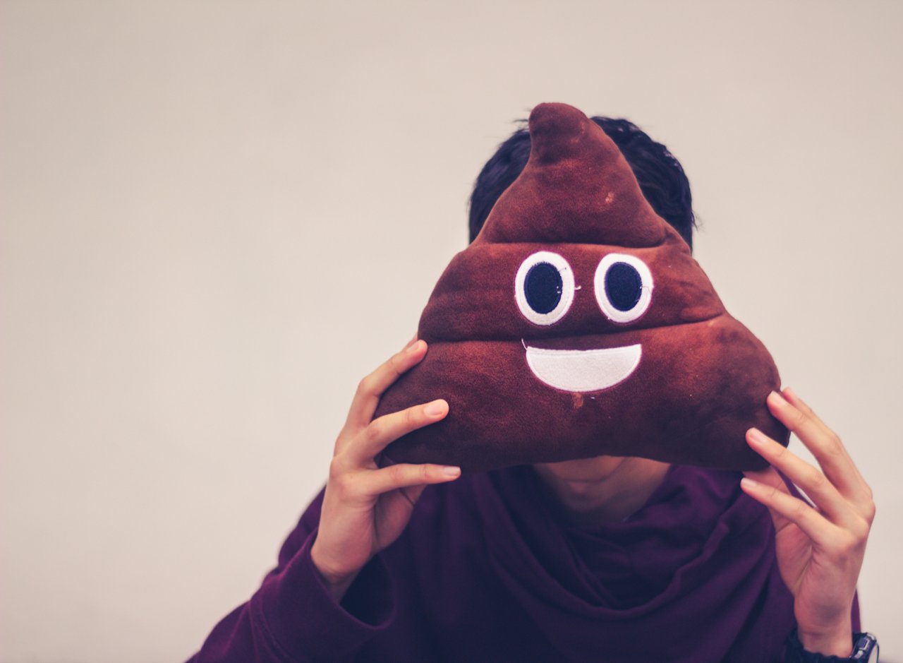 Photograph of a man with poop emoji cushion