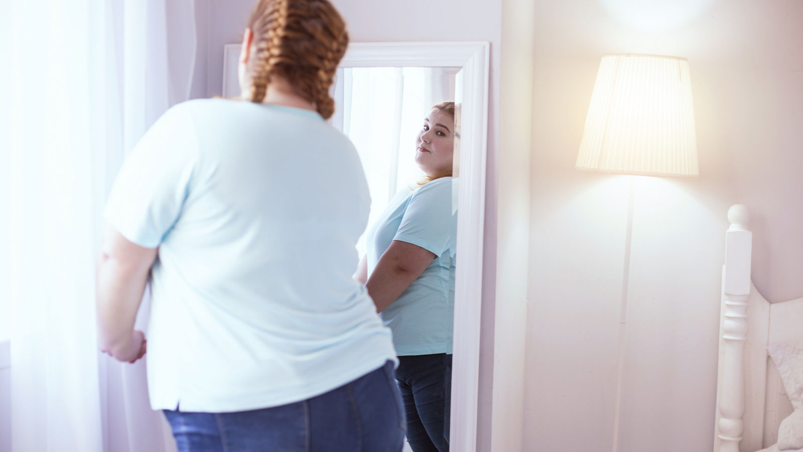 Obese woman looking at herself in the mirror