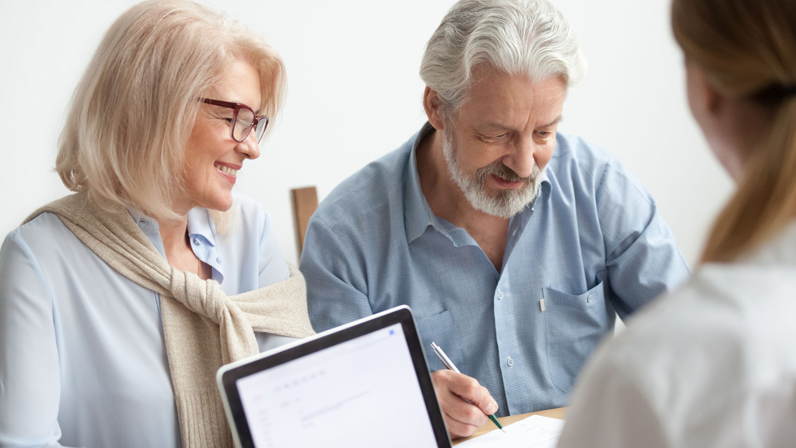 Happy senior couple signing document at meeting with financial a