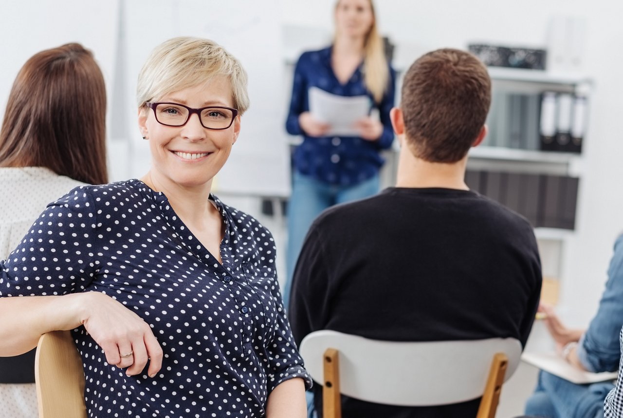 Eine glückliche Faru mit Brille lächelt in einen Meeting, während einer Versammlung