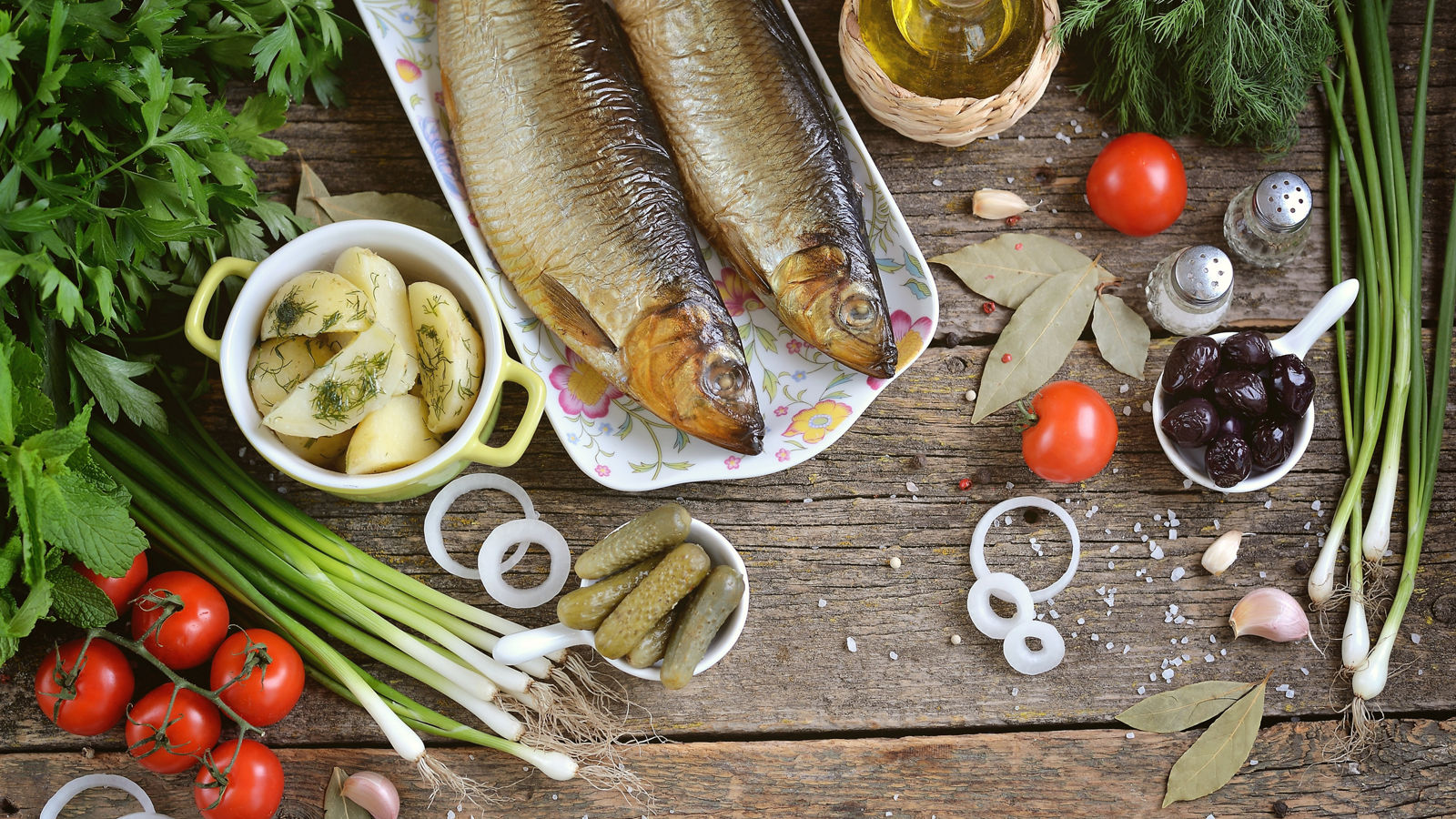 Mediterranean cuisine - smoked herring with boiled potatoes, dried olives, green onions and pickled cucumbers. Rustic style.
